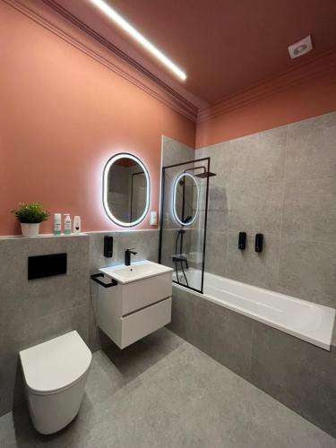 La salle de bains est pourvue de toilettes, d'un lavabo et d'une baignoire. dans l'établissement Central Gallery Apartment, à Debrecen
