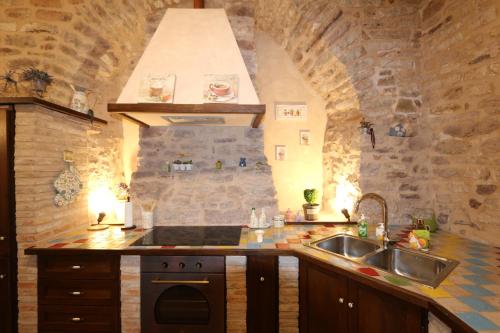 cocina con fregadero y pared de piedra en La Casina Colorata en Asís
