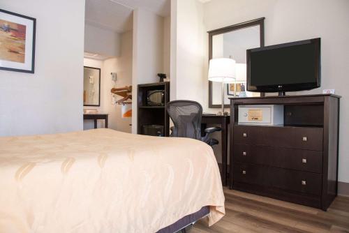 a hotel room with a bed and a flat screen tv at Quality Inn & Suites Aiken East in Aiken