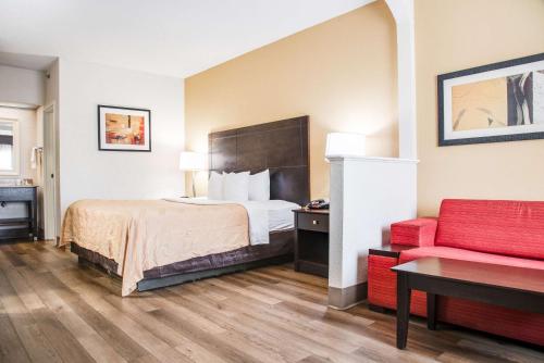 a hotel room with a bed and a red couch at Quality Inn & Suites Aiken in Aiken