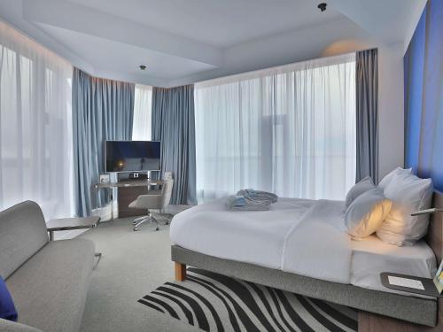 a hotel room with a large bed and a couch at Novotel Arkhangelsk in Arkhangelsk