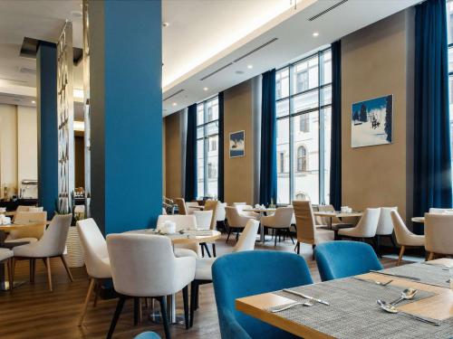 a dining room with tables and chairs and windows at Novotel Congress Krasnaya Polyana in Estosadok