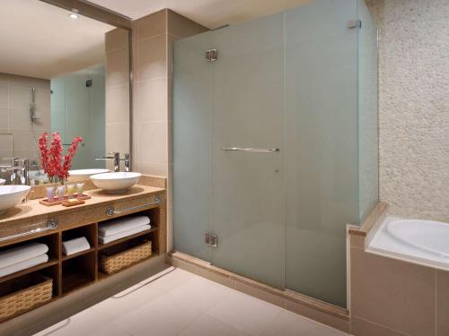 a bathroom with a glass shower and two sinks at Mövenpick Resort & Spa Tala Bay Aqaba in Aqaba