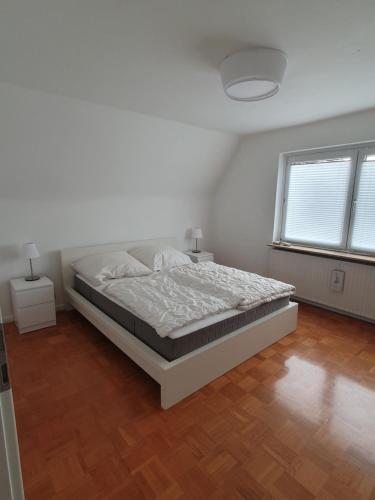 a white bedroom with a bed and two windows at FeWo-Schnoor in Lübeck