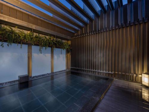 ibis Styles Tokyo Ginza East في طوكيو: مسبح داخلي بالنباتات في مبنى