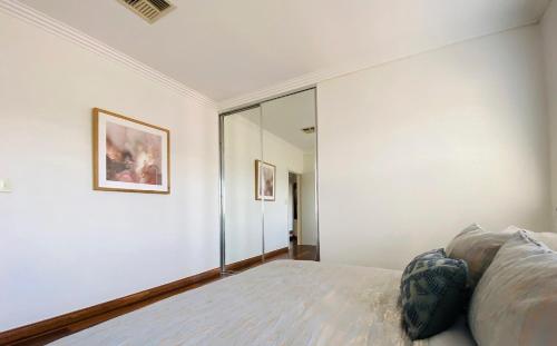 a white bedroom with a bed and a mirror at 4 bedroom family home in Riverwood in Riverwood