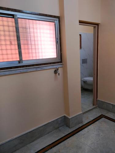 an empty bathroom with a window and a toilet at Kanan Villa in Kolkata