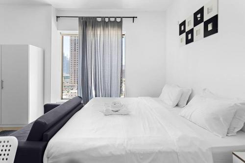 a large white bed in a room with a window at StoneTree - Elegant Studio in Peaceful Community in Dubai