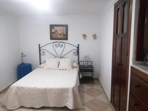 1 dormitorio con 1 cama con colcha blanca en El Rincón del Marqués en Alcalá de los Gazules