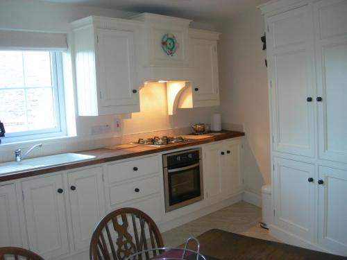 una cocina con armarios blancos y fregadero en Templemoyle Farm Cottages en Campsey