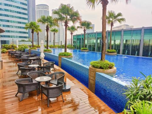 a hotel pool with tables and chairs and palm trees at Vortex suites near by KLCC in Kuala Lumpur