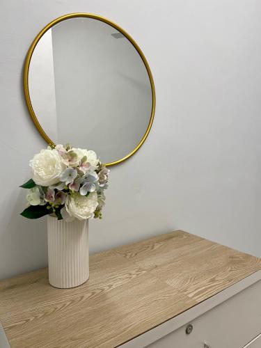 a vase of flowers on a table with a mirror at DOUBLETHREE Seroja Sepang in Sepang
