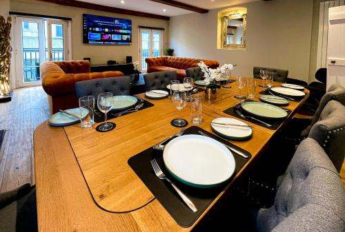 a long wooden table with plates and glasses on it at The Coach House - Your luxury private Brighton getaway with private parking in Brighton & Hove