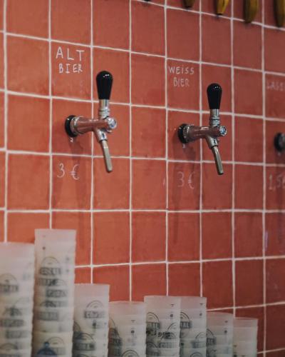 a bathroom with two faucets and toilet paper on a wall at Jaca Hostel Funchal in Funchal