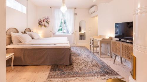 een slaapkamer met een bed, een bureau en een televisie bij Villa Maija 3 Westside in Hanko