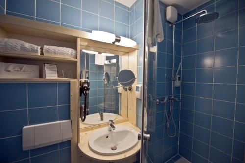 ein blau gefliestes Bad mit einem Waschbecken und einem Spiegel in der Unterkunft Sporthotel Heiligenblut in Heiligenblut