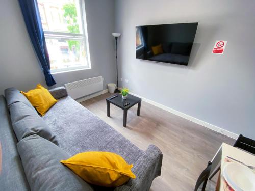 sala de estar con sofá gris y almohadas amarillas en MODERN 1 BEDROOM FLAT IN WOOD GREEN en Londres
