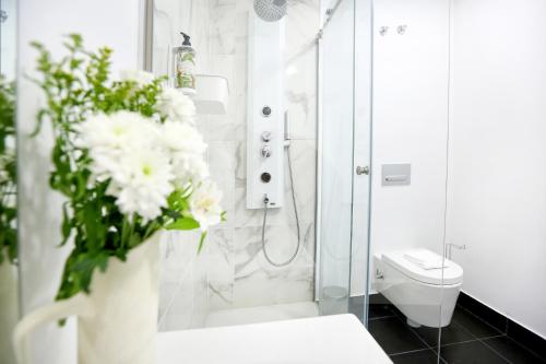 a bathroom with a shower and a toilet and a vase of flowers at Xtraordinary Moments Apartment in Faro