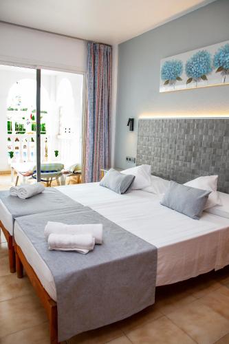a bedroom with two beds with towels on them at Atalaya Bosque Apartamentos in Paguera
