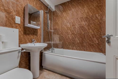 a bathroom with a sink and a tub and a toilet at The Waterloo Apartment - Large Private Patio & Air Conditioning in London