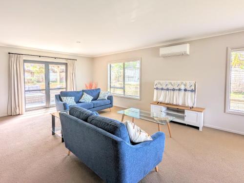 a living room with two blue couches and a table at Make yourself Home in Rotorua
