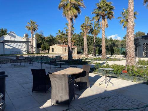 a patio with a table and chairs and palm trees at Maison d Hotes BLUE PALM Aix en PROVENCE in Aix-en-Provence