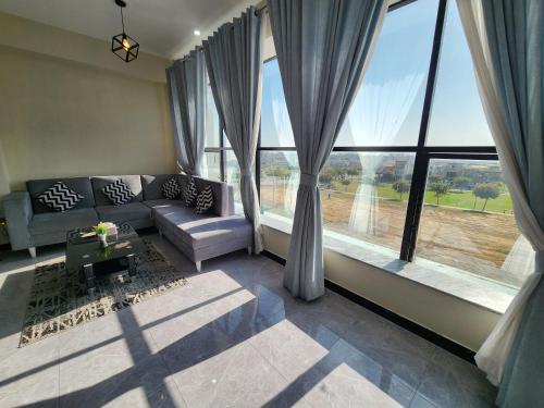 a living room with a couch and large windows at Motorway Majesty Suites Islamabad - Near Islamabad International Airport and Motorway in Islamabad