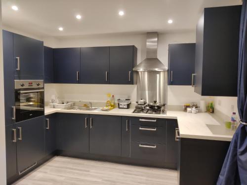 uma cozinha com armários azuis escuros e um fogão em Cosyhome em Wellingborough