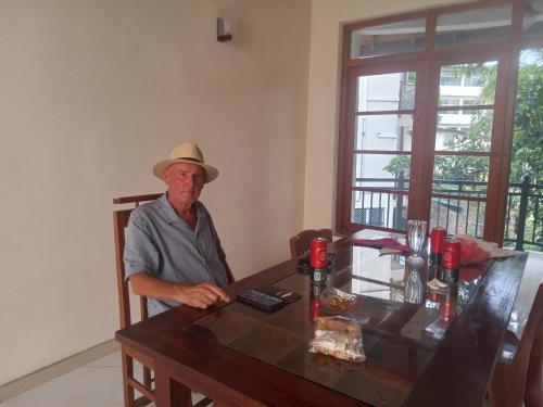 a man in a hat sitting at a table at MALWATHTHA MOUNT VILLA KANDY in Kandy