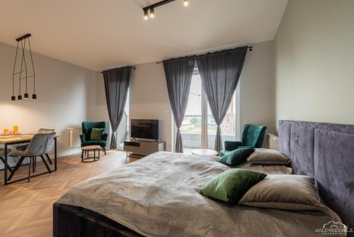 a bedroom with a large bed and a table and chairs at Horyzont Apartamenty- Studio- SAUNA&FITNESS -BAŁTYCKA 2- ŚNIADANIA in Kołobrzeg