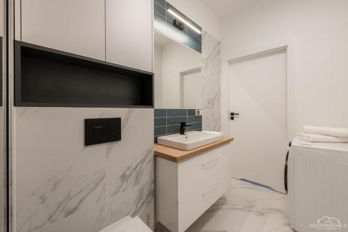 a white bathroom with a sink and a toilet at Horyzont Apartamenty- Studio- SAUNA&FITNESS -BAŁTYCKA 2- ŚNIADANIA in Kołobrzeg