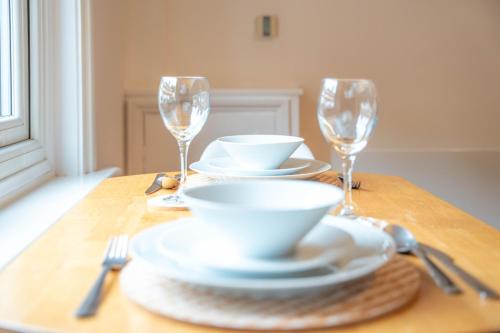einen Tisch mit Tellern und Weingläsern darauf in der Unterkunft Redhill Garland- 1 bed ground floor apartment by LGW Short Lets in Redhill