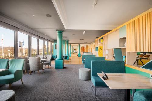 a waiting room with blue chairs and tables and windows at Holiday Inn Leeds Brighouse, an IHG Hotel in Brighouse
