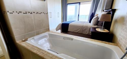 een badkamer met een bad en een slaapkamer bij Whale Rock 9 - Sleeps 6 - with Inverter - 30m from the beach - 70m from the Margate Pier - 180 Degree sea view in Margate