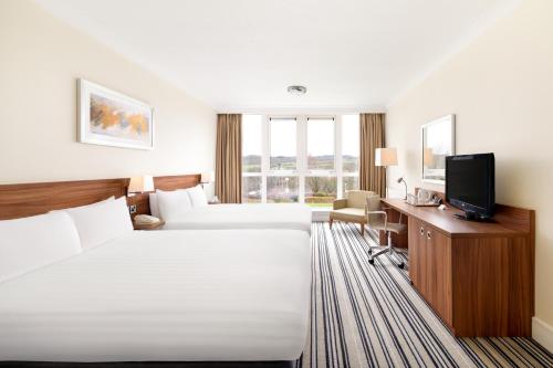 ブリッグハウスにあるHoliday Inn Leeds Brighouse, an IHG Hotelのベッド2台とテレビが備わるホテルルームです。
