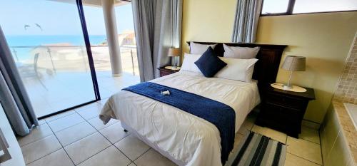 een slaapkamer met een bed en uitzicht op de oceaan bij Whale Rock 9 - Sleeps 6 - with Inverter - 30m from the beach - 70m from the Margate Pier - 180 Degree sea view in Margate