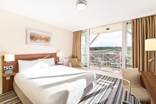 Holiday Inn Leeds Brighouse, an IHG Hotel في برغهاوس: غرفة فندقية بسرير ونافذة كبيرة