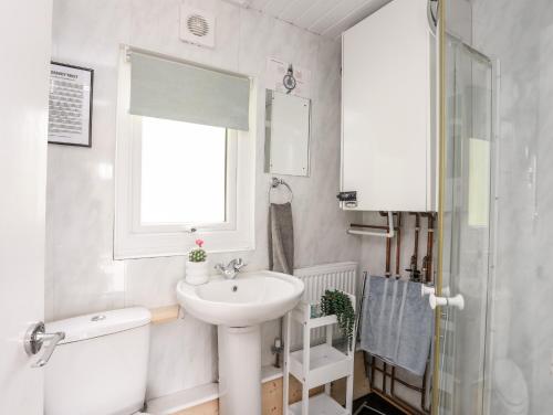 łazienka z umywalką, toaletą i oknem w obiekcie Sundowner w mieście Caernarfon