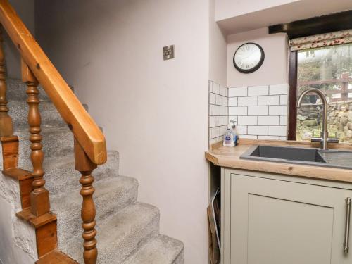 a kitchen with a staircase and a clock on the wall at Moorside Cottage in Oxenhope