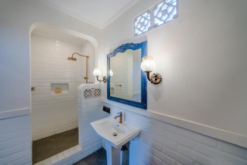 a white bathroom with a sink and a mirror at Pitaloka Hotel Sanur By DeWizZ Management in Sanur