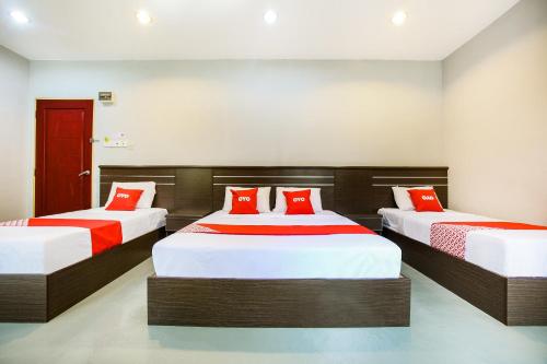um quarto com 2 camas e almofadas vermelhas em OYO 89660 Raudhah Inn Hotel em Kampong Bukit Kechil