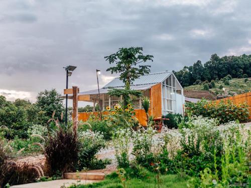 a garden with flowers and a building in the background at Phu Morinn Cafe &Camping Monjam in Mon Jam