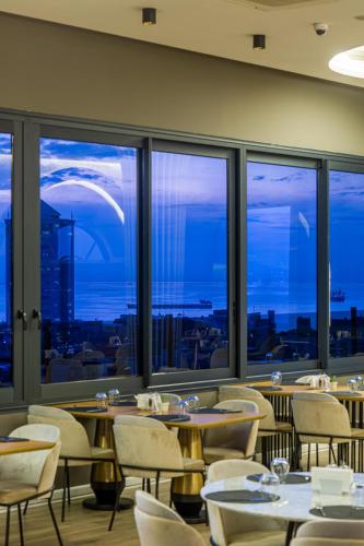 a restaurant with tables and chairs and a view of the city at DoubleTree by Hilton Izmir - Alsancak in Izmir
