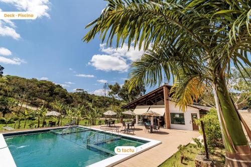 a resort with a swimming pool and a palm tree at Triplex em condomínio de Guaramiranga por Tactu in Guaramiranga