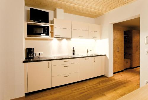 a kitchen with white cabinets and a wooden floor at Das Tannberg in Lech am Arlberg