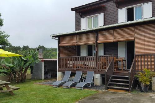 a house with a deck with chairs on it at Chalet Floricia974, meublé de tourisme in Saint-Paul