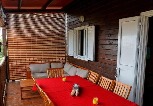 a red table and chairs on a porch with a couch at Chalet Floricia974, meublé de tourisme in Saint-Paul