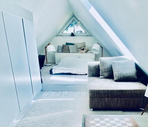 Cette chambre mansardée comprend un lit et un canapé. dans l'établissement Beautiful House in Blankenese, à Hambourg