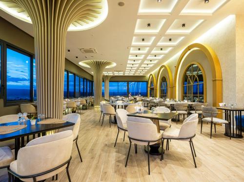 a restaurant with tables and chairs and windows at DoubleTree by Hilton Izmir - Alsancak in Izmir