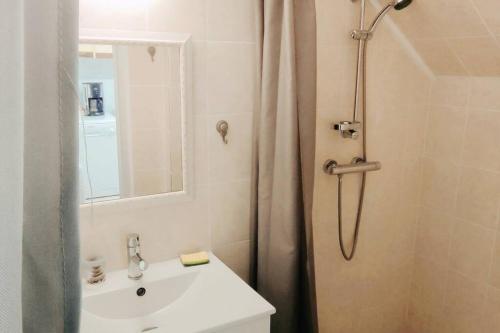 uma casa de banho branca com um chuveiro e um lavatório. em Maison d'hôtes Decastela em Thiviers